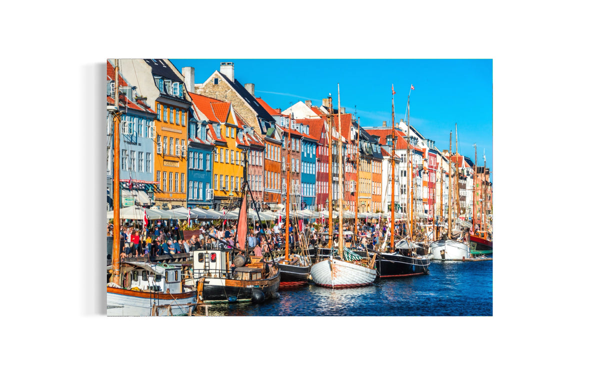 Nyhavn print of colorful townhouses, sailboats and café terraces along the Copenhagen canal, shown as a mounted print