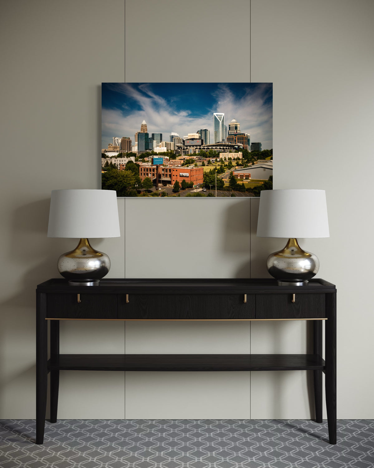 Queen City print above a black console table with two silver lamps
