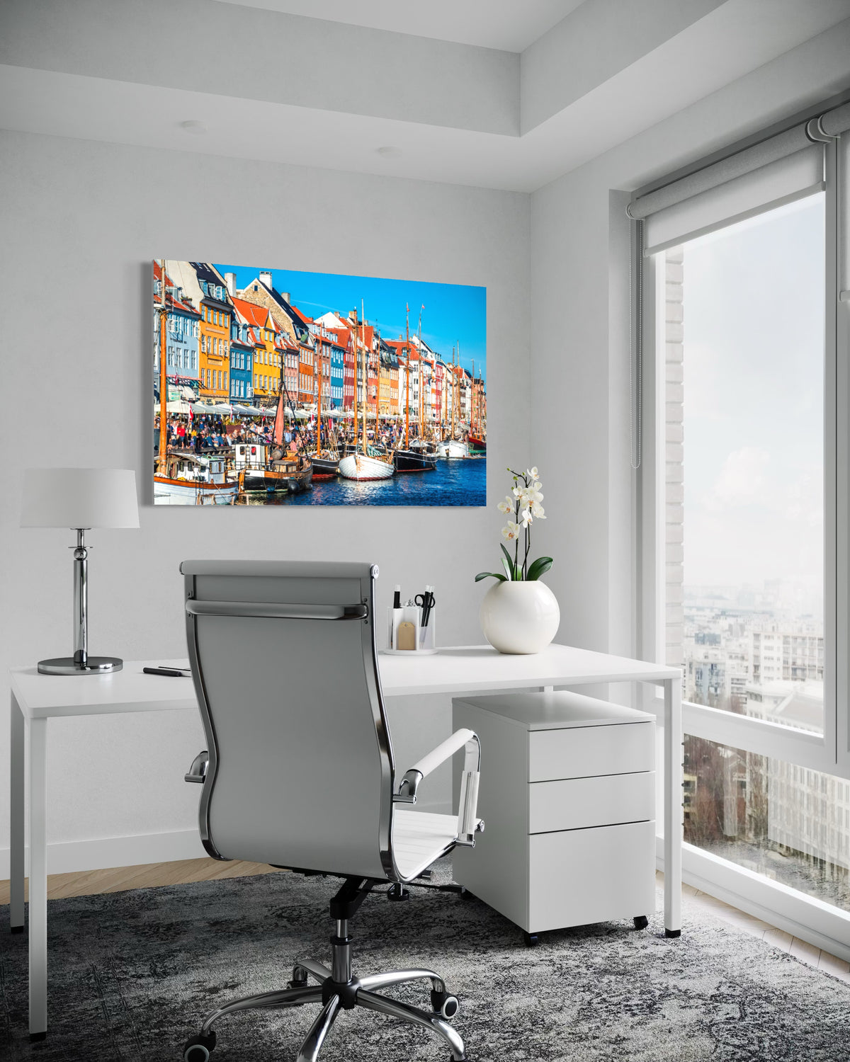 Nyhavn harbor print on the wall above a white desk in a home office with a large window