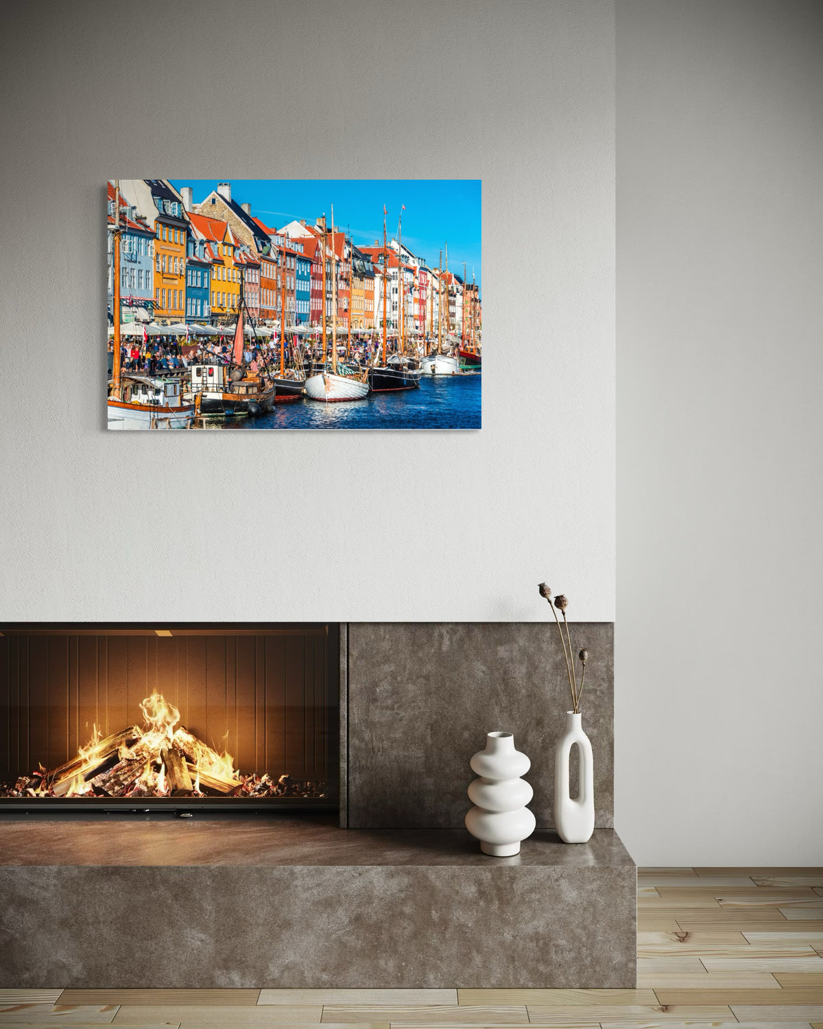 Nyhavn print hung above a modern fireplace with a stone hearth and white ceramic vases
