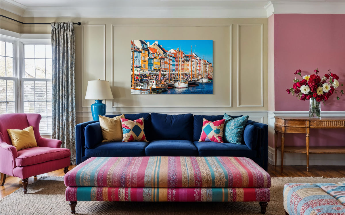 Nyhavn print of Copenhagen's colorful harbor houses and wooden boats hung above a navy velvet sofa in a living room
