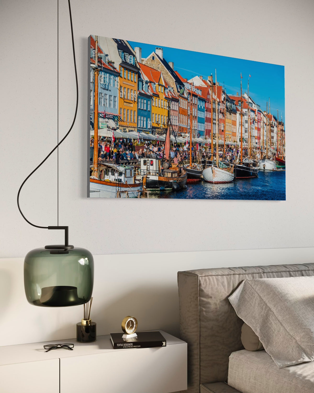 Nyhavn print on a bedroom wall above a nightstand with a smoked-glass pendant lamp
