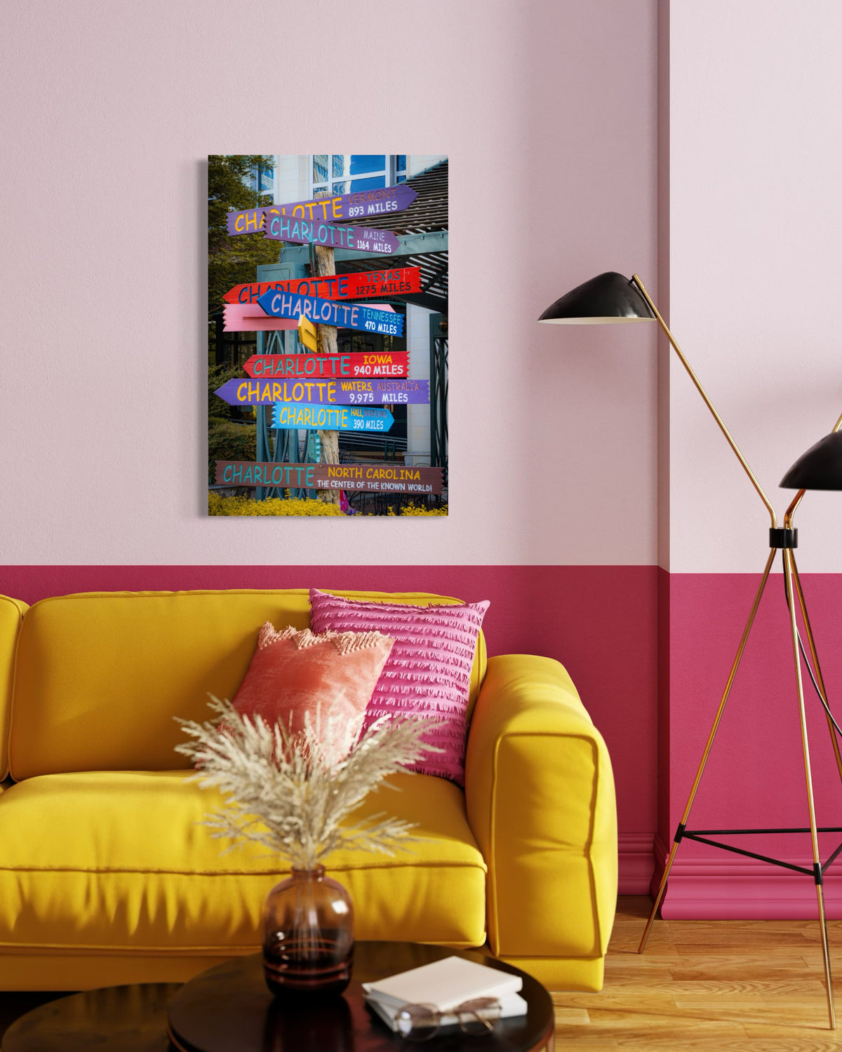 Directions print on a pink wall above a yellow sofa with pink pillows, beside a black floor lamp