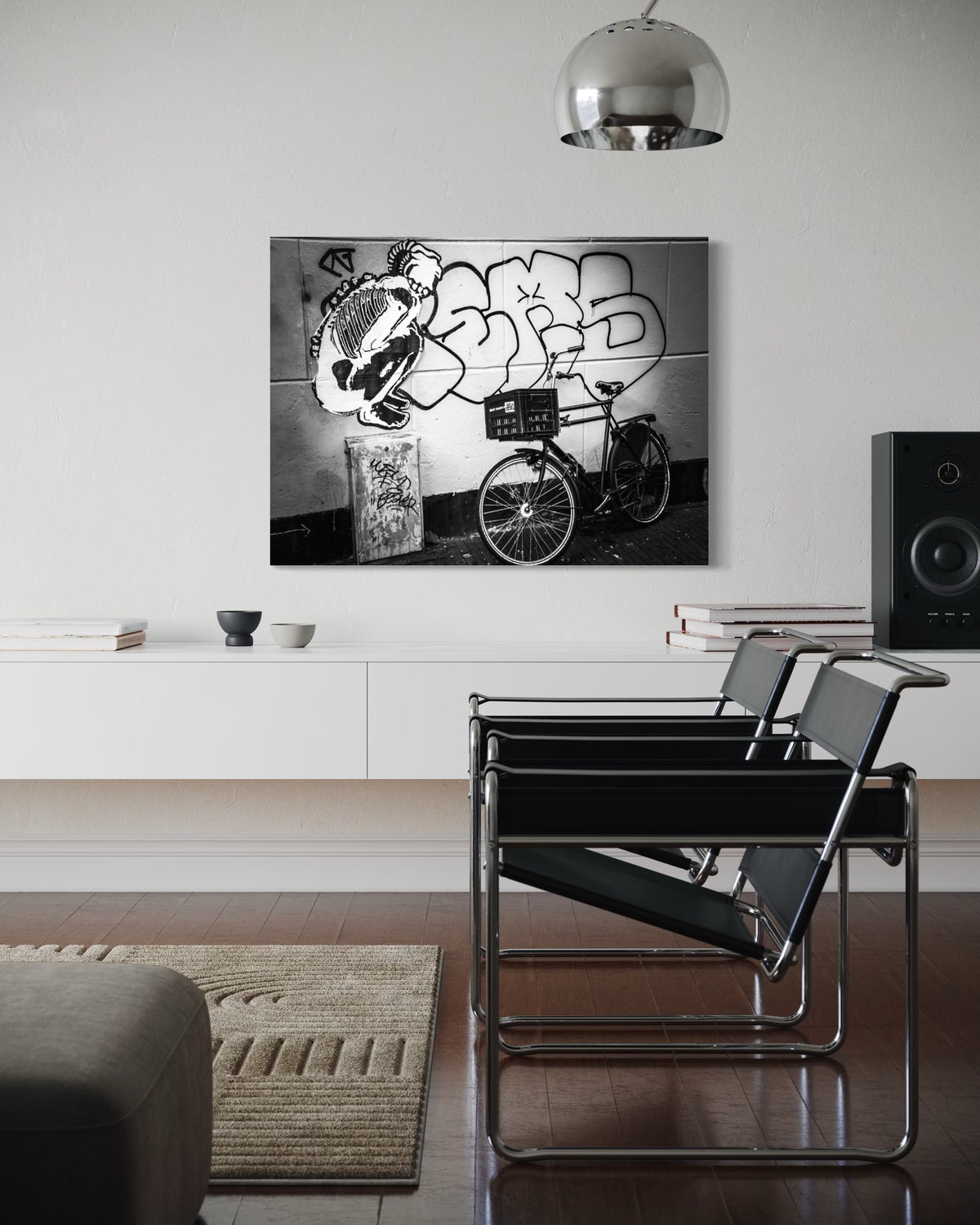 Street & Steel print above a white low cabinet, beside two black sling chairs under a chrome dome pendant lamp