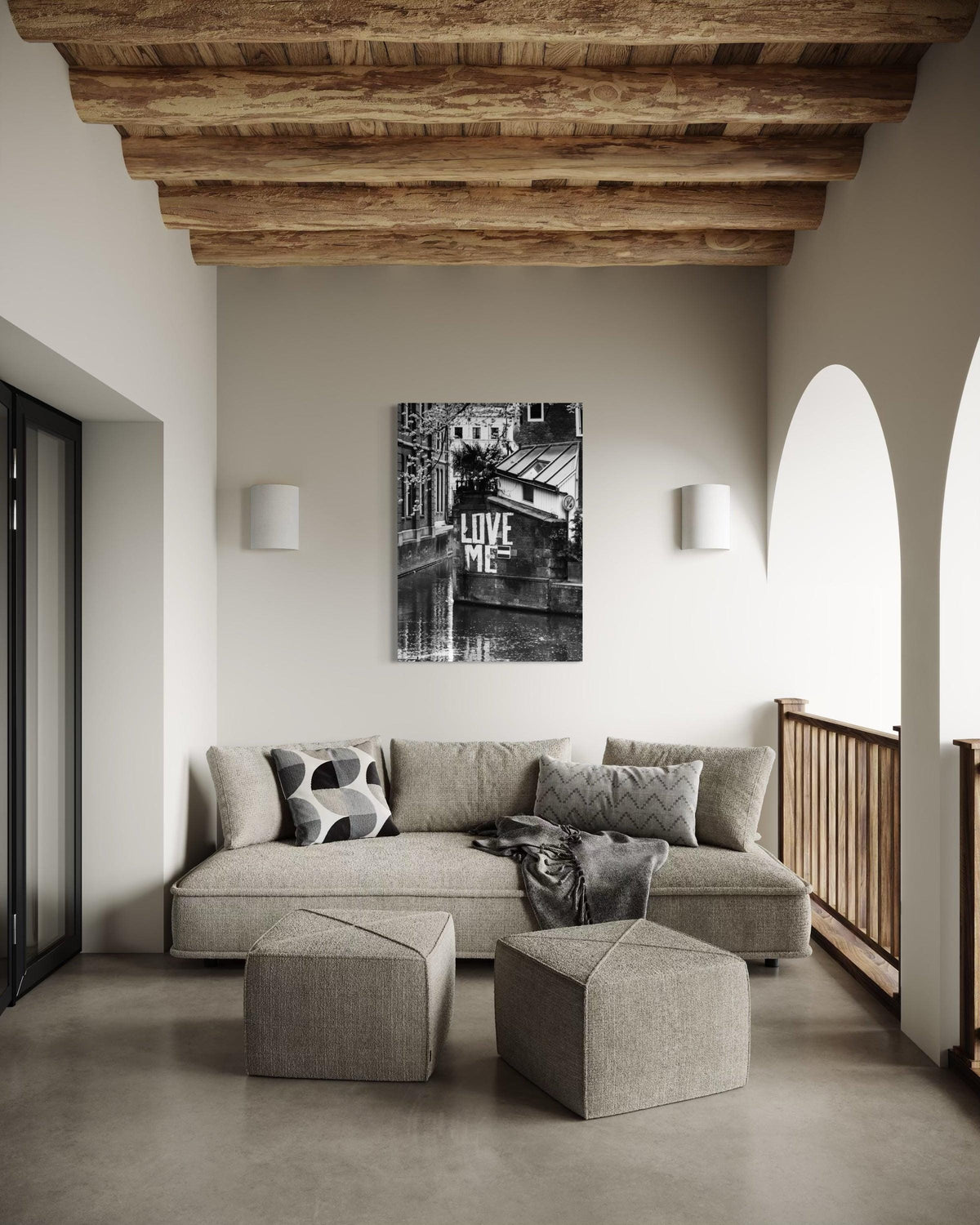 Love Me black and white print above a beige sofa in a room with a wooden beam ceiling and arched openings